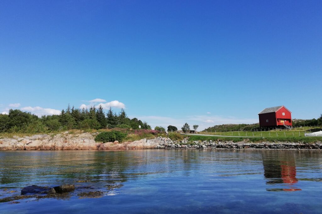Drvena crvena kućica na obali Norveškog mora u Vallersund gardu.