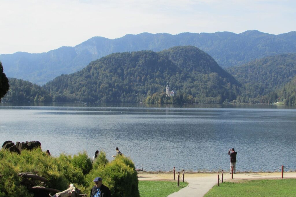 Muškarac okrenut leđima fotografira jezero Bled u Sloveniji.