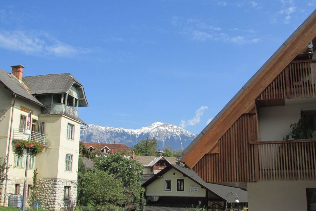 Krovovi kuća između kojih se vidi vrh planine Triglav u blizini jezera Bled u Sloveniji.