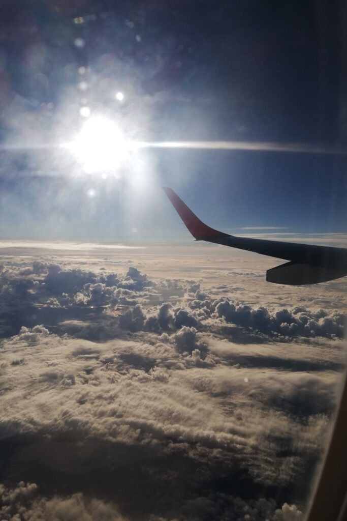 Pogled na oblake i sunce kroz prozor u avionu.