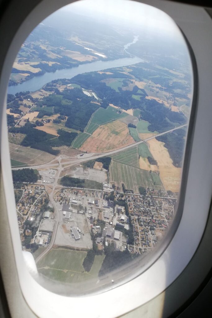 Pogled iz prozora u avionu prema poljima i rijeci.